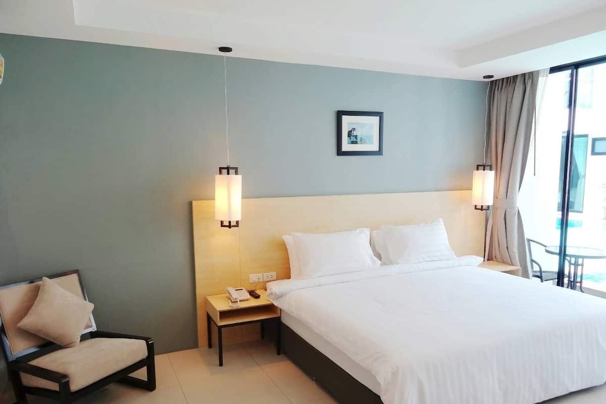 Habitación de hotel con una cama grande, una mesita de noche con teléfono, una silla y un cuadro en la pared.