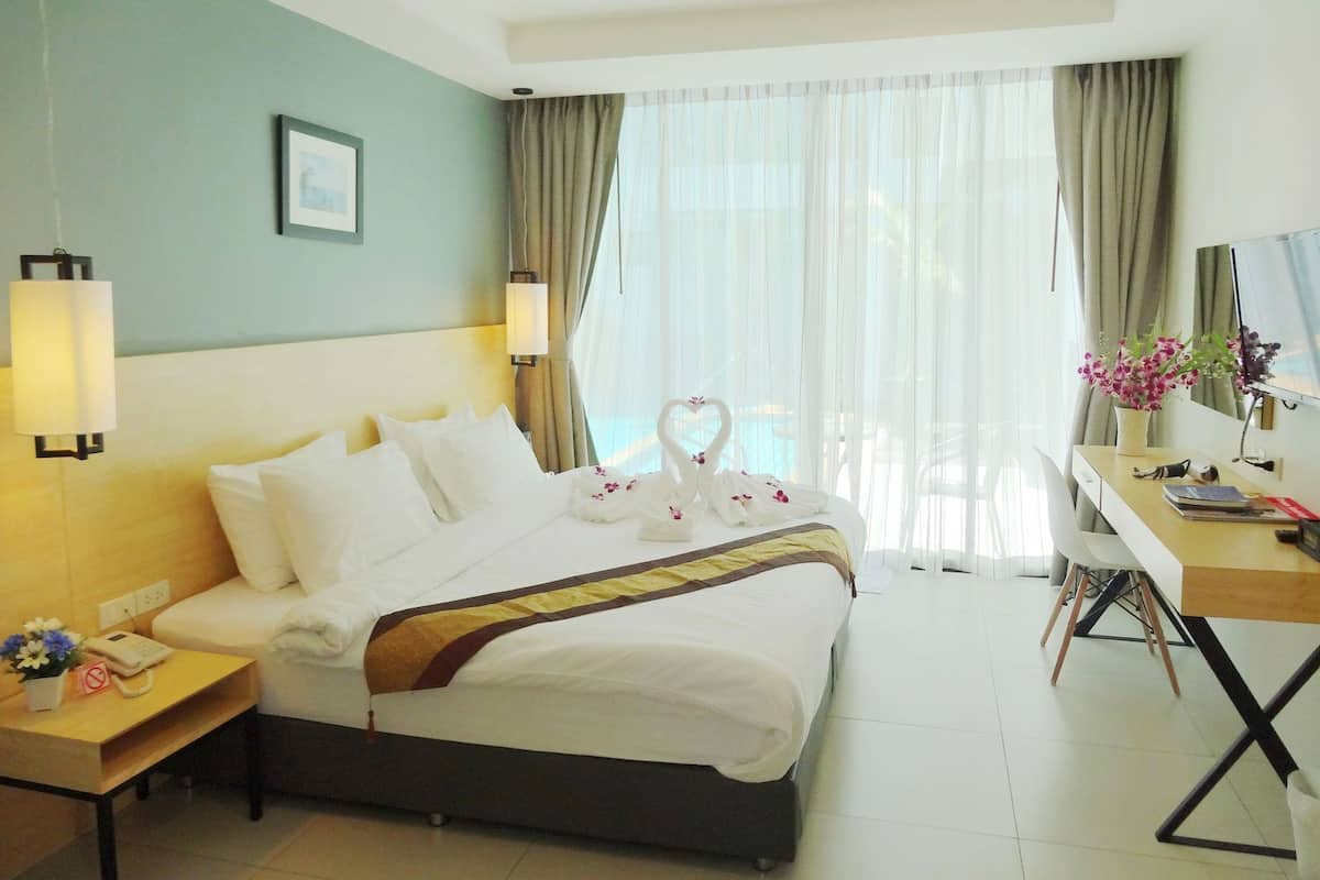 Habitación de hotel con cama, mesitas de noche, escritorio, silla, ventana con cortinas y televisor montado en la pared.