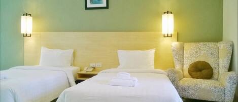 A hotel room with two beds, a nightstand, a chair, and two wall-mounted lamps.