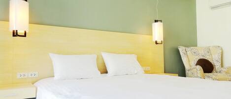 A hotel room with a large bed, two bedside tables, a chair, and wall-mounted lights.