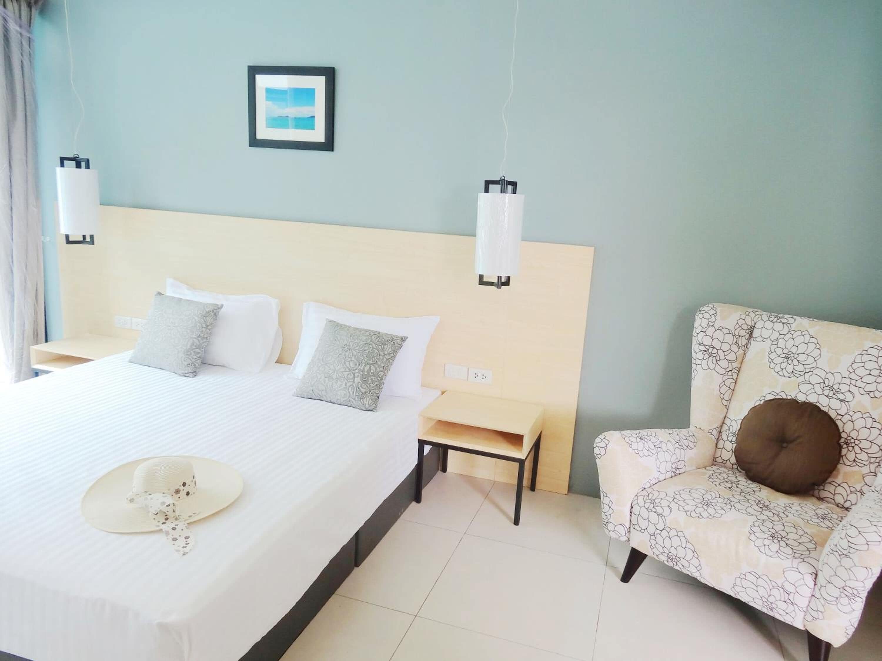 A hotel room with a large bed, a chair, and a picture on the wall.