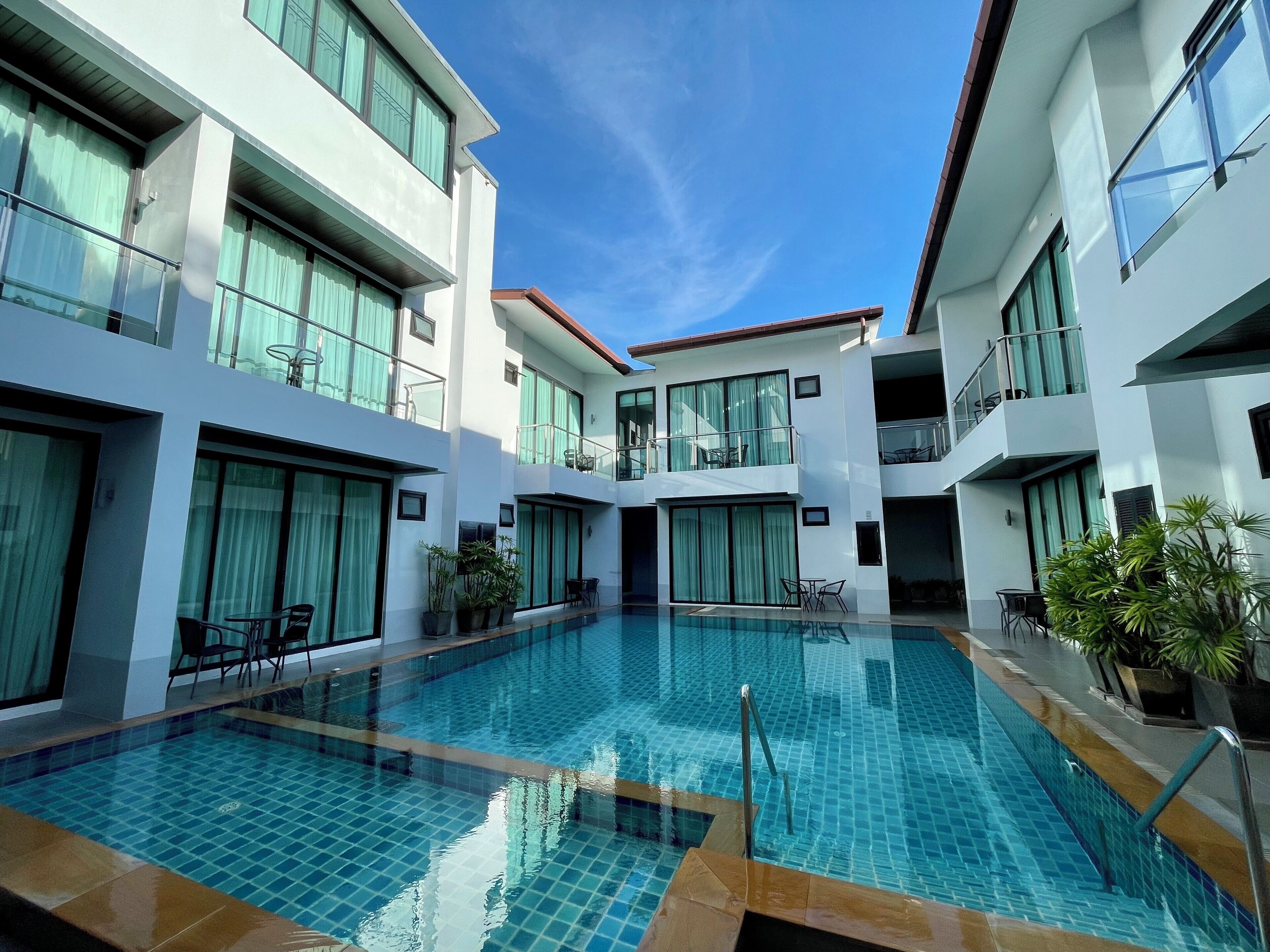 Un hotel moderno con piscina central, varios balcones y ventanas amplias.