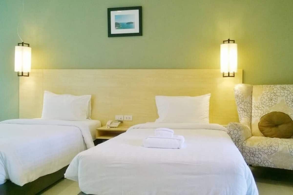 Habitación de hotel con dos camas, una silla y una mesita de noche con teléfono.