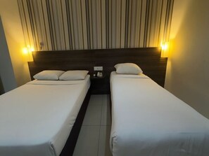 A hotel room with two single beds, a striped wall headboard, and bedside lamps.