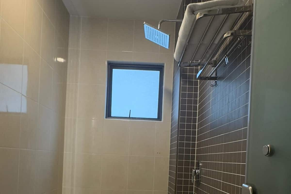 A modern bathroom with a shower, a toilet, and a window.