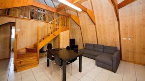 Un interior de madera con una escalera, una mesa de comedor y un sofá.