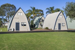 A row of small, triangular-shaped cabins with a flat roof, each featuring a door and a window.