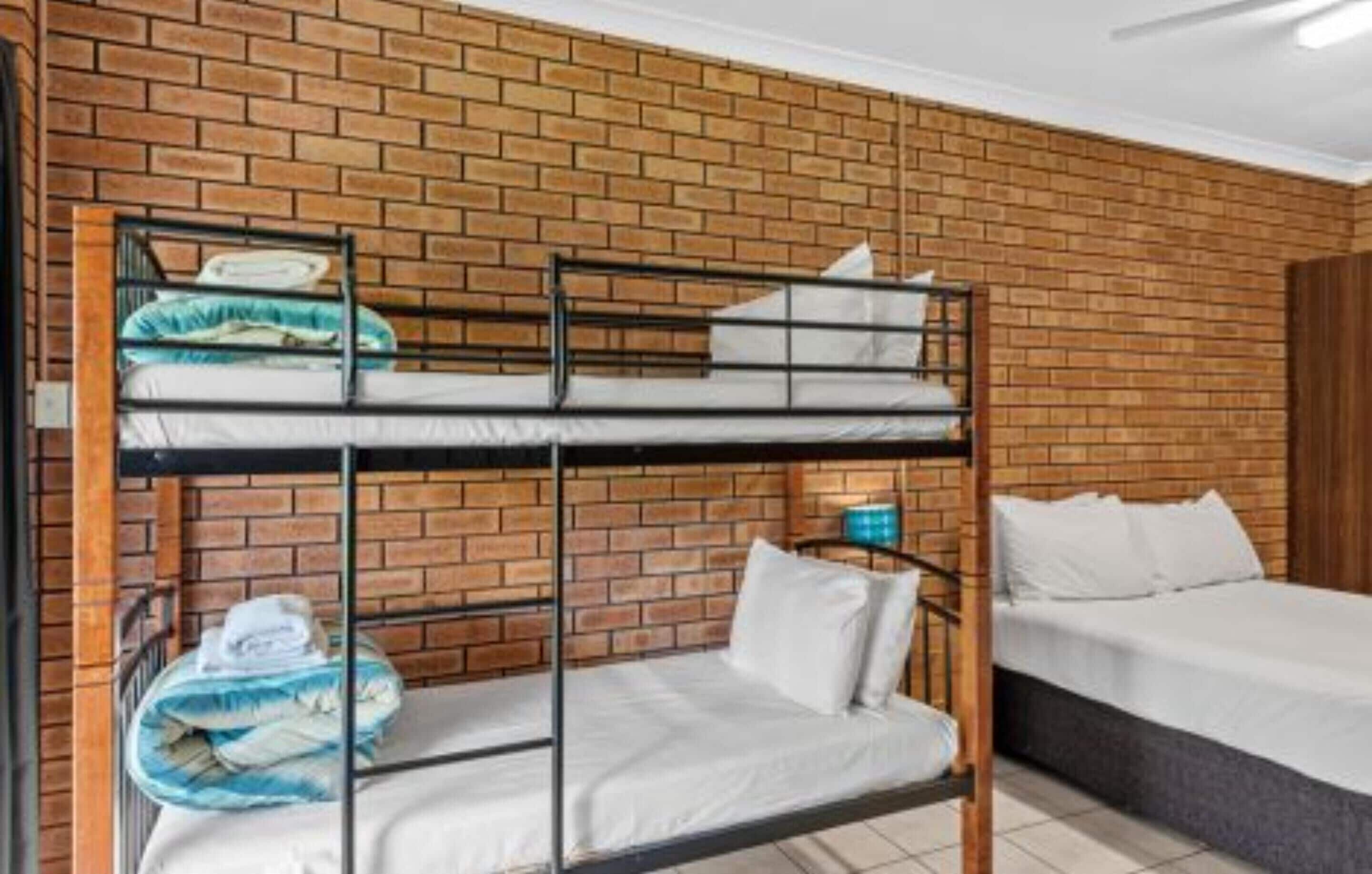 Een slaapkamer met een stapelbed, een bakstenen muur en een enkel bed.