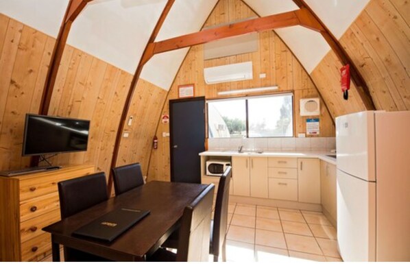 A cozy, wooden interior with a dining area, kitchen, and a television.