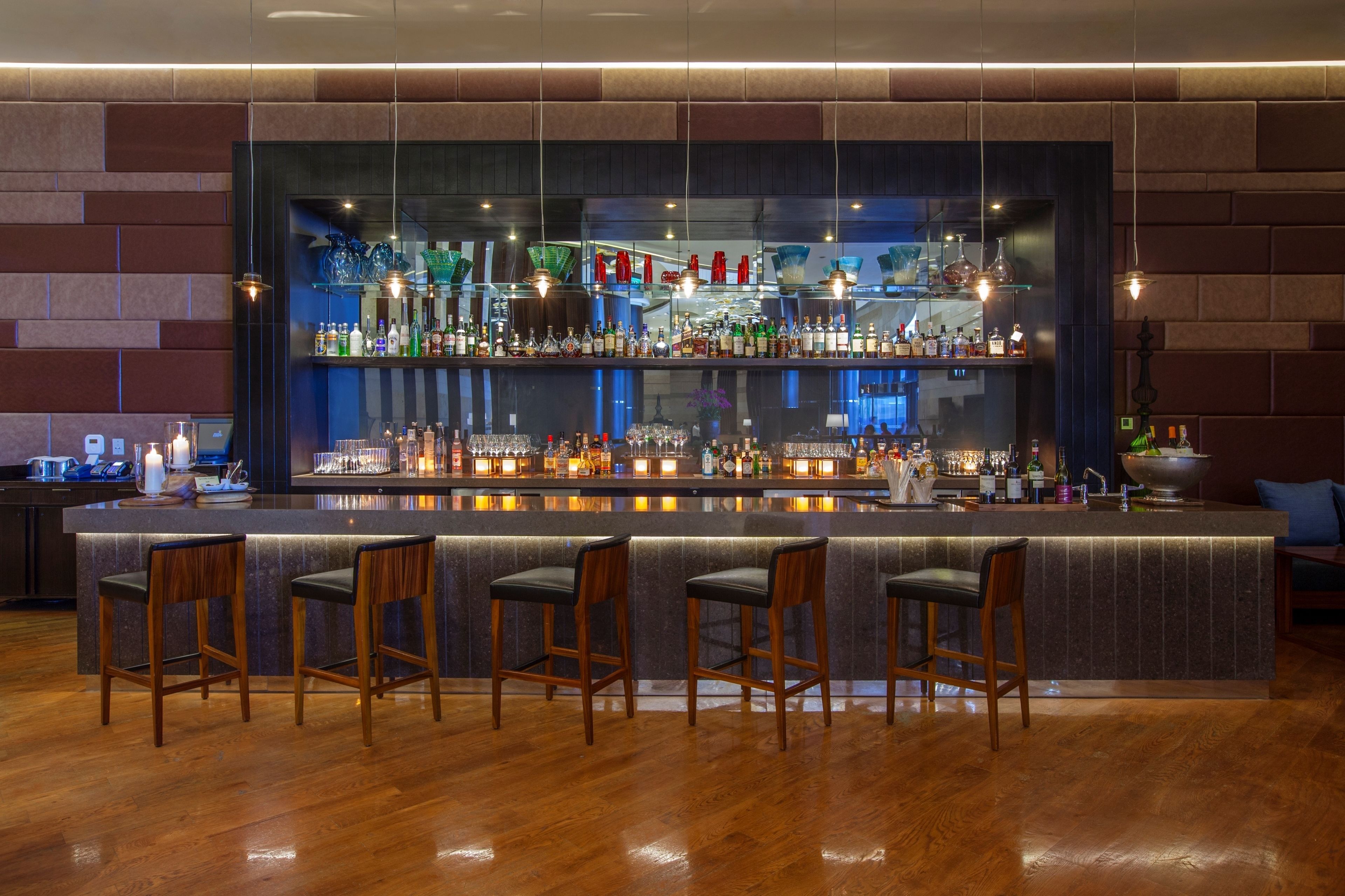 Eine Bar mit einer langen Theke, zahlreichen Flaschenregalen und Barhocker.