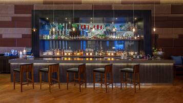 Eine Bar mit einer langen Theke, zahlreichen Flaschenregalen und Barhocker.
