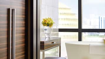 A modern bathroom with a marble floor, a white bathtub, a towel rack, and a vase with flowers on a vanity.