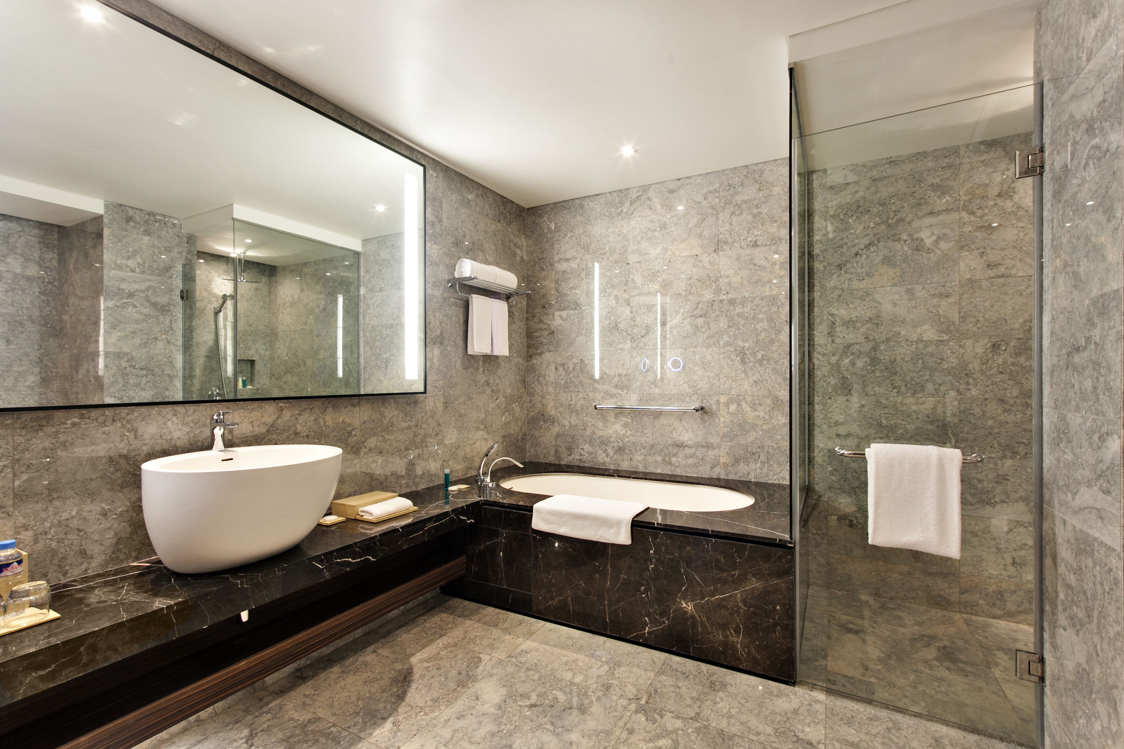 A modern bathroom with a large sink, a bathtub, and a glass shower enclosure.