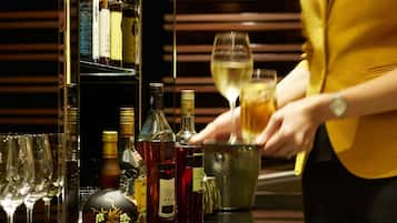 Un barman preparando una bebida en la barra, con varias botellas y vasos.