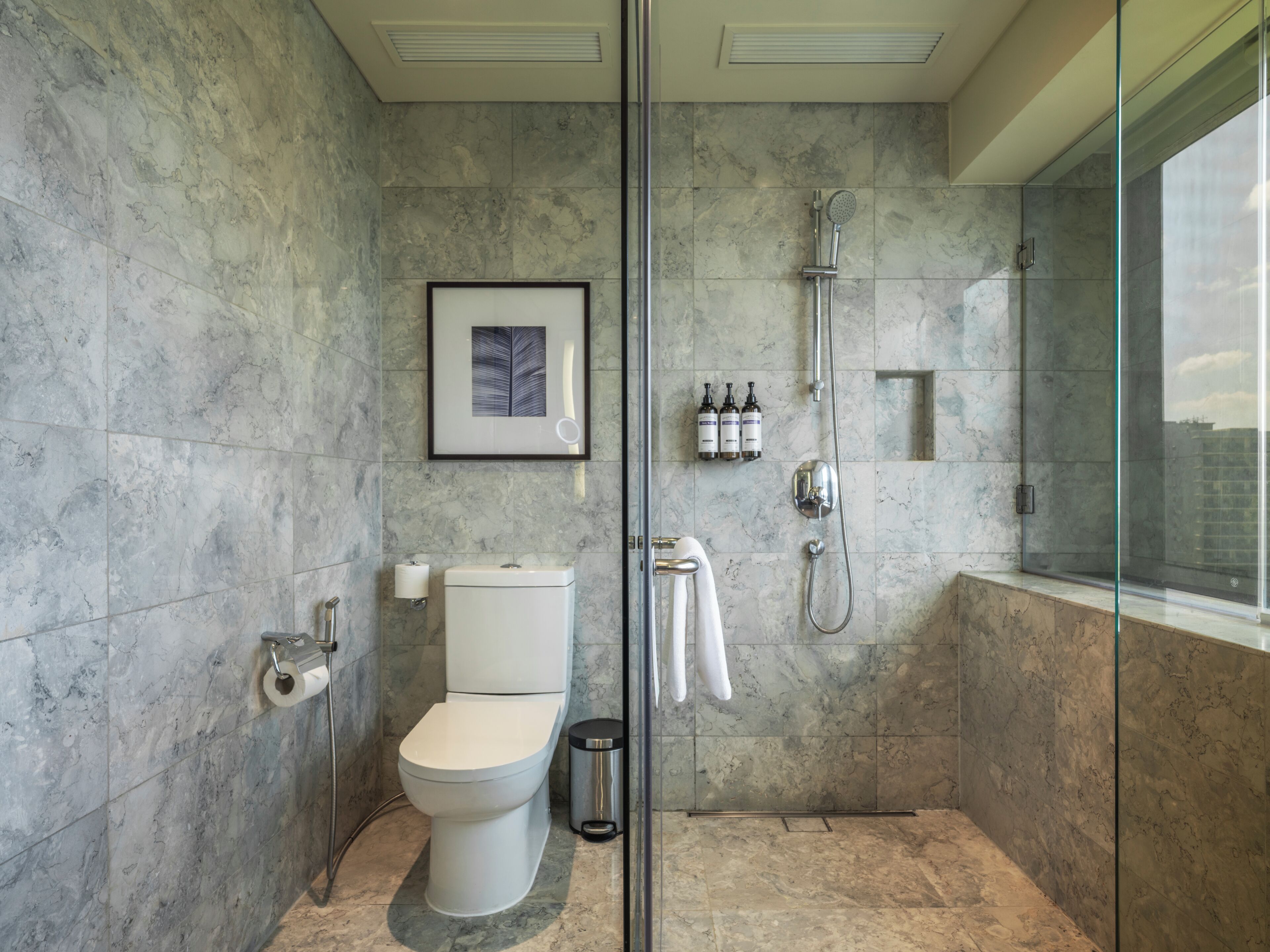 A modern bathroom with a toilet, shower, and glass enclosure.