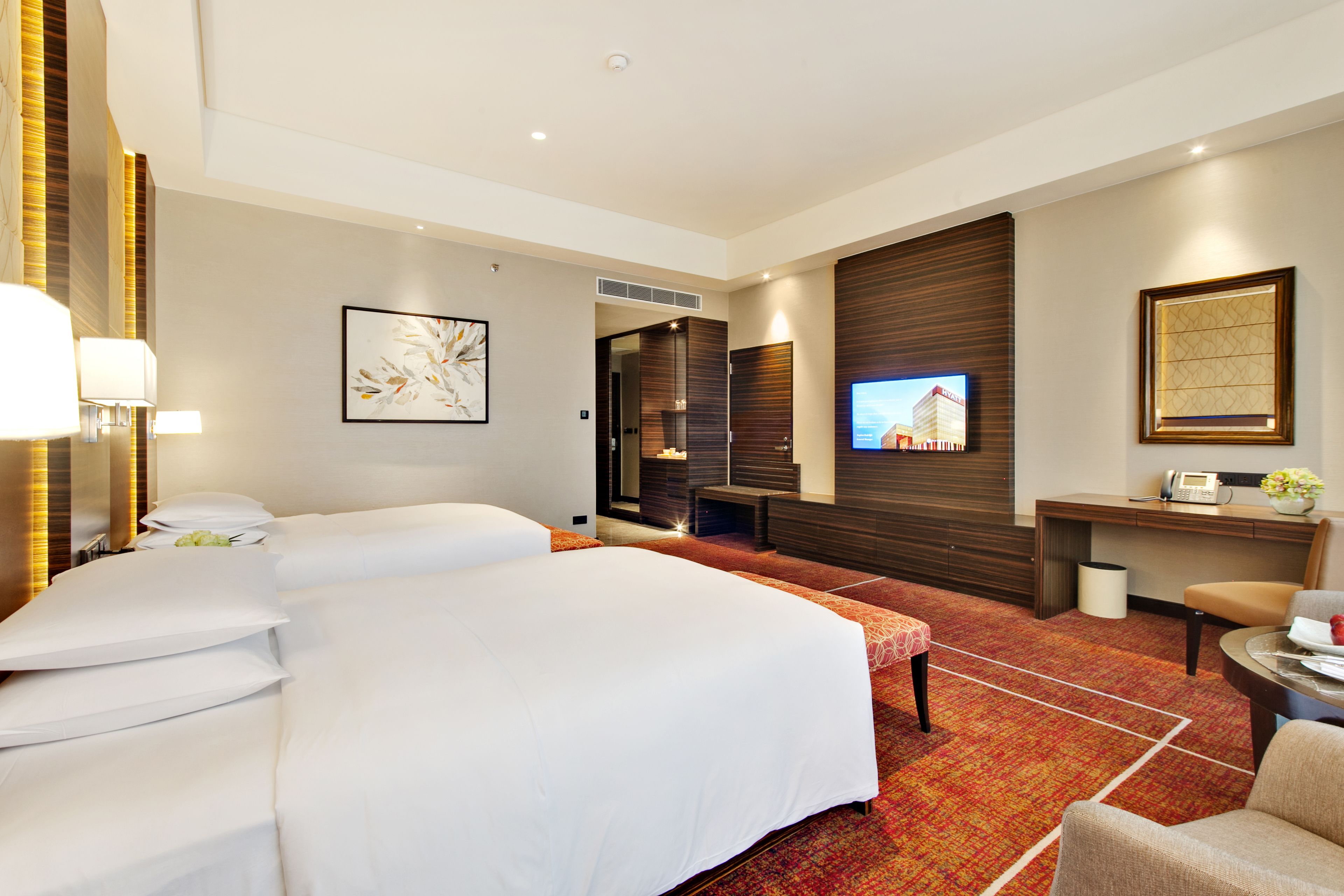 A hotel room with a large bed, a desk with a computer, a TV, and a seating area.