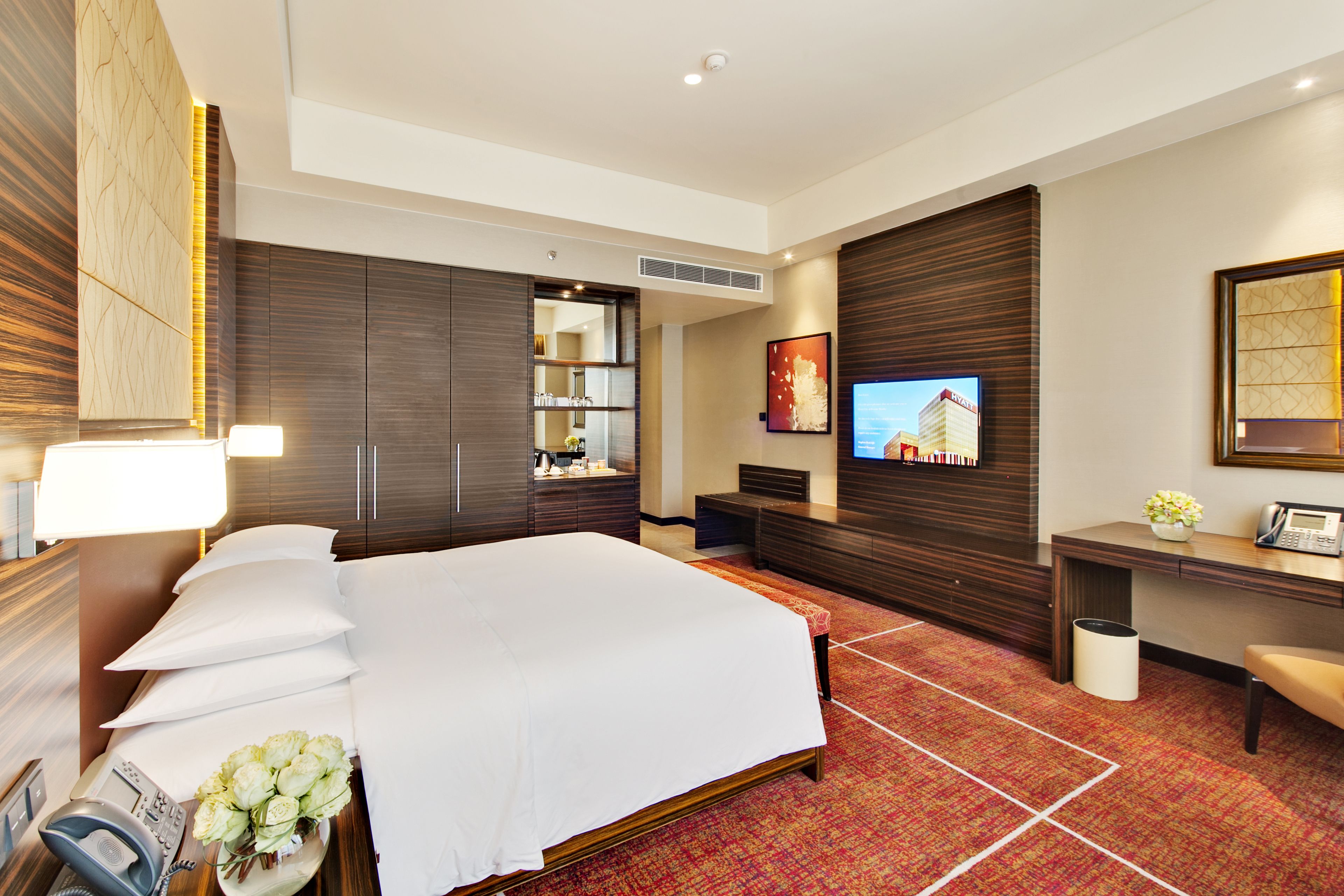 Una habitación de hotel con una cama grande, un escritorio con teléfono, televisión y espejo.
