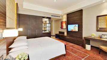 Una habitación de hotel con una cama grande, un escritorio con teléfono, televisión y espejo.
