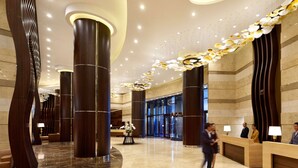 A spacious lobby with high ceilings, large wooden columns, and a modern chandelier. - Hyatt Regency Manila, City of Dreams (Parañaque)