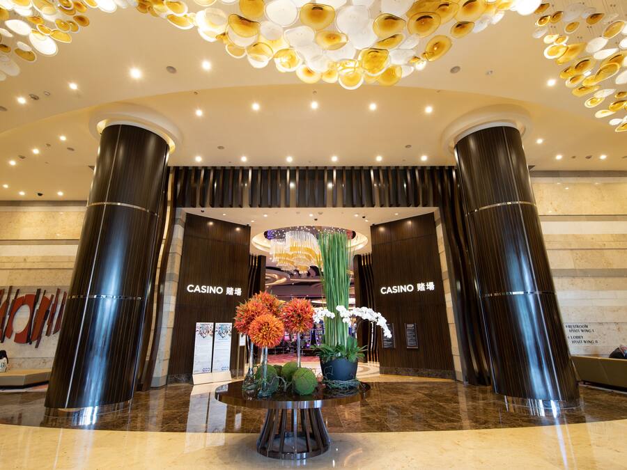 A lobby with a central floral arrangement, two large pillars, and a ceiling with circular light fixtures.