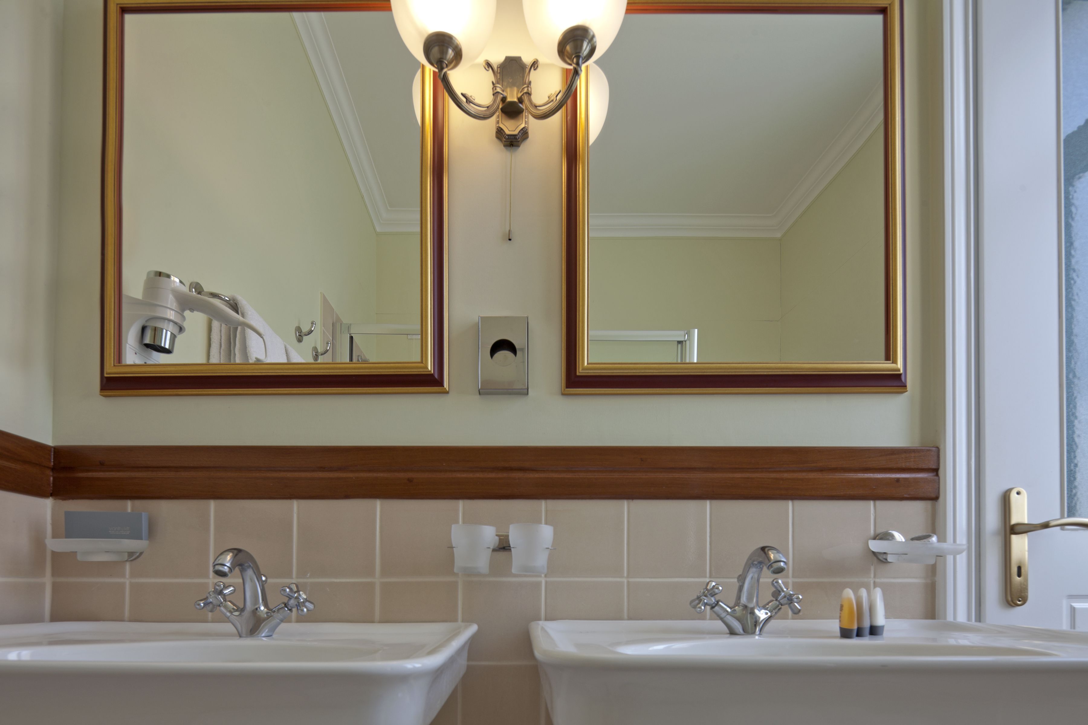 Ein Badezimmer mit zwei Waschbecken, einem großen Spiegel und einer Kristallleuchtre.