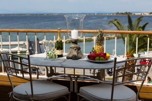 Een tafel met champagne, een kaars en een fruitschaal op een balkon met uitzicht op zee.