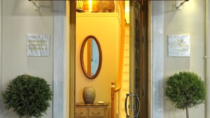 The entrance to the Boschetto Hotel with a checkered floor, a mirror, and two potted plants. - Hotel Boschetto (Lefkada)