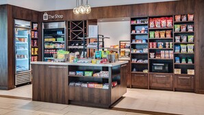 Un épicerie dotée d’un espace central où sont exposés divers produits et articles de première nécessité, ainsi que des rayons réfrigérés et des étagères remplies d’en-cas et de produits emballés.
