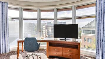Un espacio de oficina moderno con un escritorio grande, una silla y un televisor de pantalla plana.