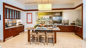 Une cuisine moderne dotée d’un îlot central, de meubles en bois et d’un bar pour prendre le petit-déjeuner.
