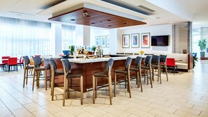 Une cuisine moderne dotée d’un îlot central, de tabourets de bar et d’un coin repas avec des chaises rouges.