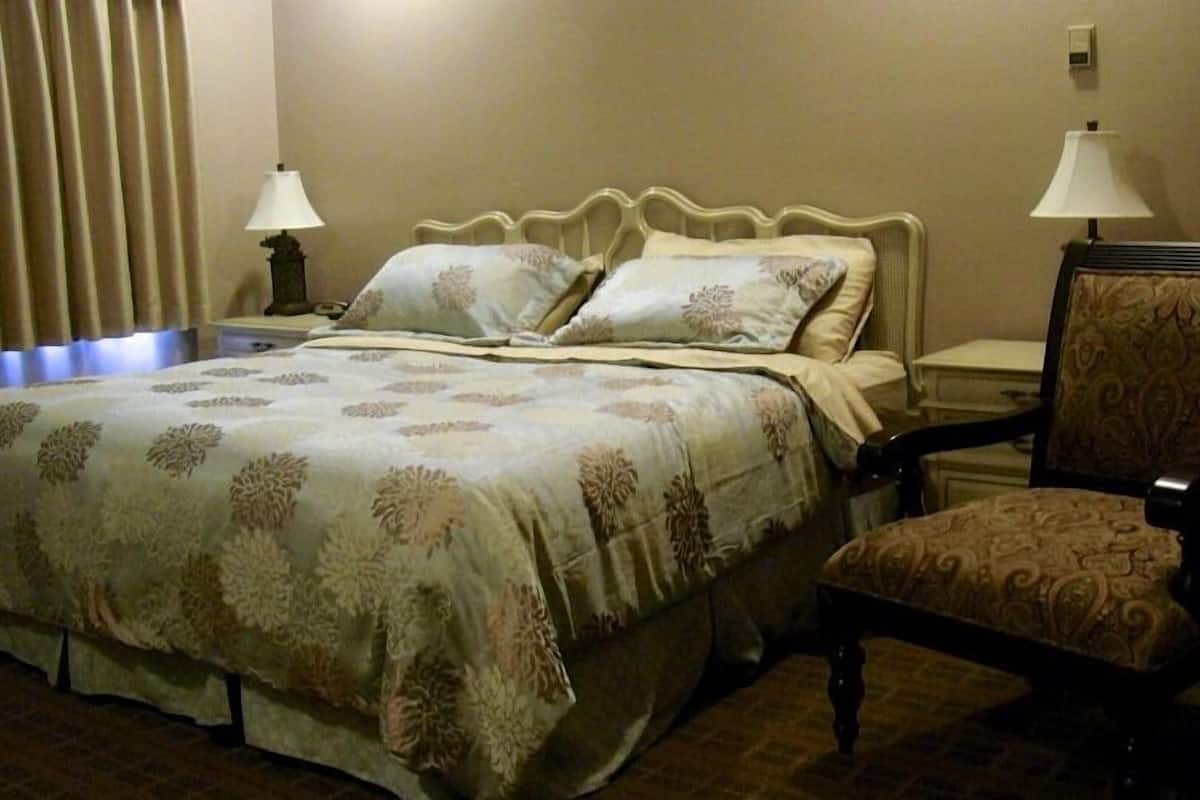 Ein Hotelzimmer mit einem Bett, zwei Nachttischlampen, einem Sessel und einem Nachttisch.