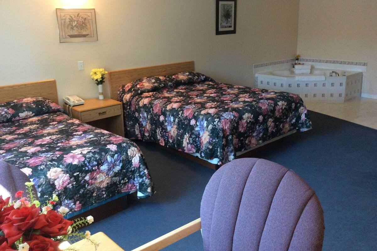 Una habitación de hotel con dos camas, un sofá, una mesita de noche, un teléfono y un jarrón con flores.