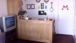 A kitchen with wooden cabinets, a refrigerator, a sink, and a television displaying a sports game. - Rainbow Motel (Swift Current)