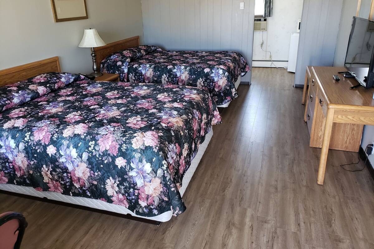 Una habitación de hotel con dos camas, un escritorio de madera y una televisión.