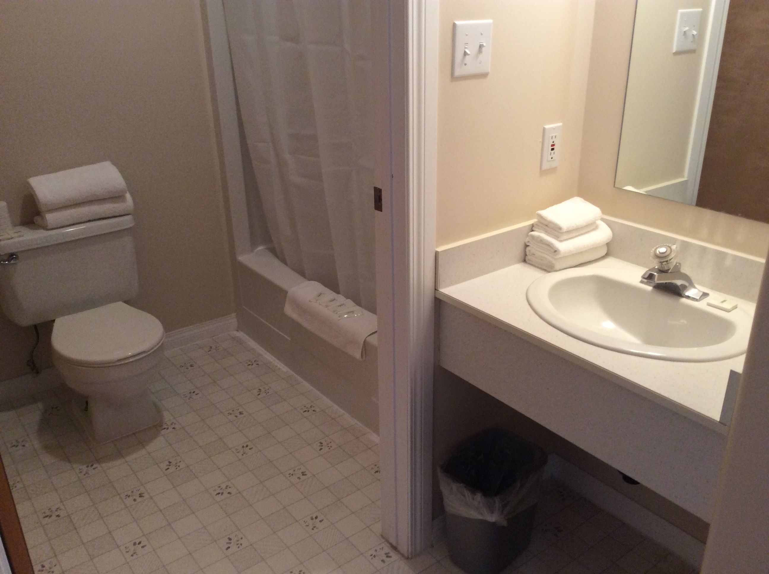 Un baño con inodoro, ducha, lavabo y un cubo de basura.