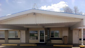 A building with a flat roof, a covered entrance, and a sign indicating a vacancy. - Rainbow Motel (Swift Current)