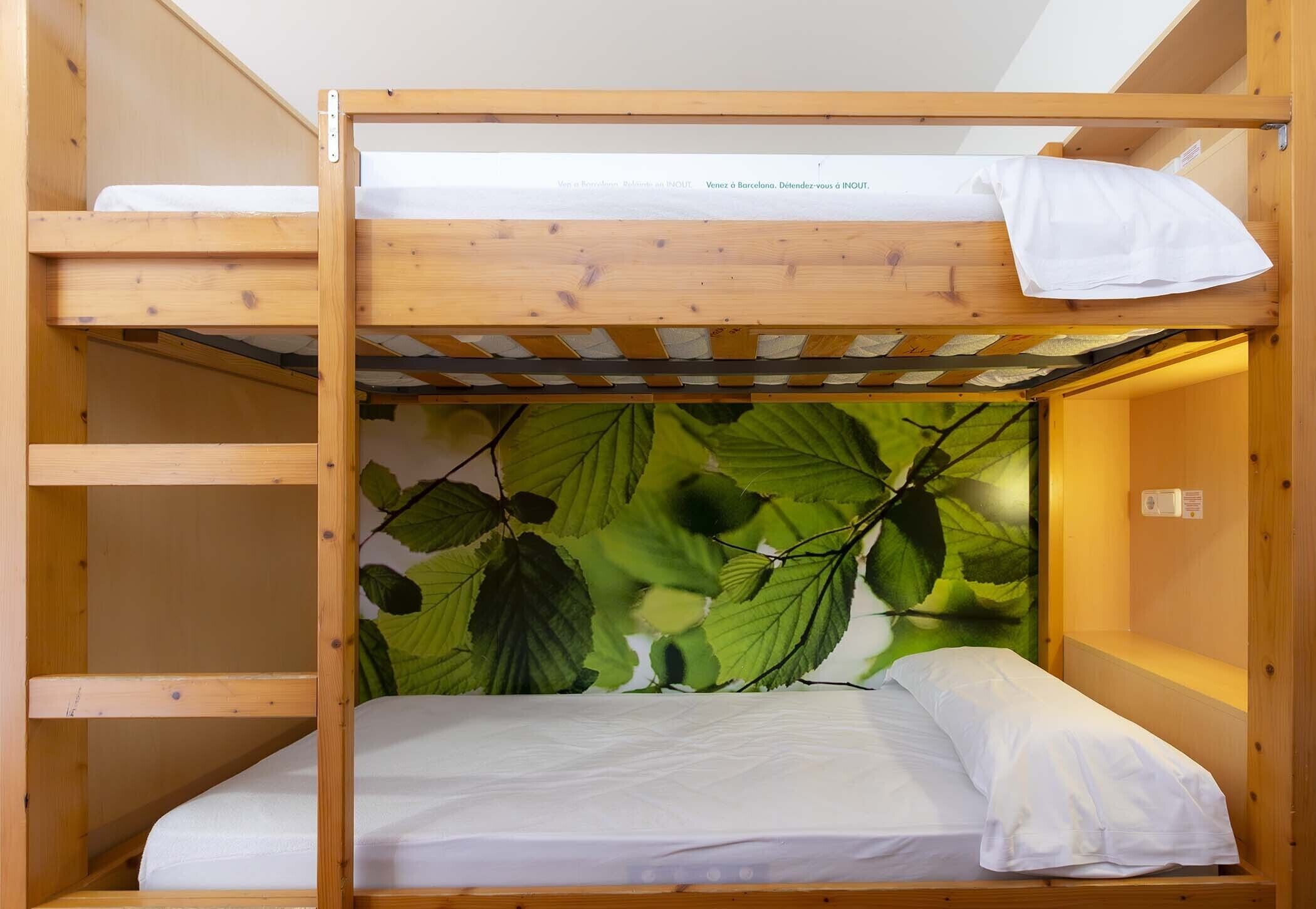 A bunk bed with a leaf-patterned wall, a white pillow, and a wooden headboard.