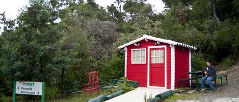 A red building with a white door and windows, a bench, and a sign indicating a reception and restaurant.