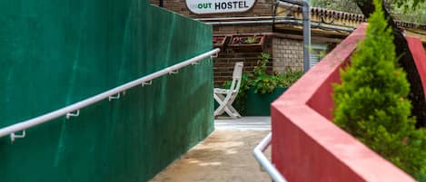 A hostel entrance with a sign reading "WELCOME TO IN OUT HOSTEL" and a brick wall.
