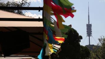Un mât sur lequel flottent des drapeaux aux couleurs vives, un ciel dégagé et, au loin, une haute tour de communication.
