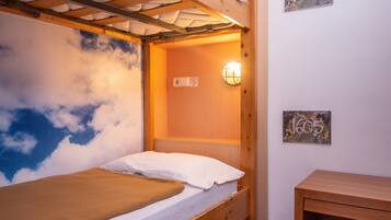 A bunk bed with a wooden headboard, a small bedside table, and a wall-mounted light fixture.