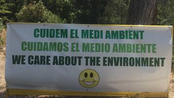 A sign with a smiley face, stating "CUIDEM EL MEDIO AMBIENTE" and "WE CARE ABOUT THE ENVIRONMENT".