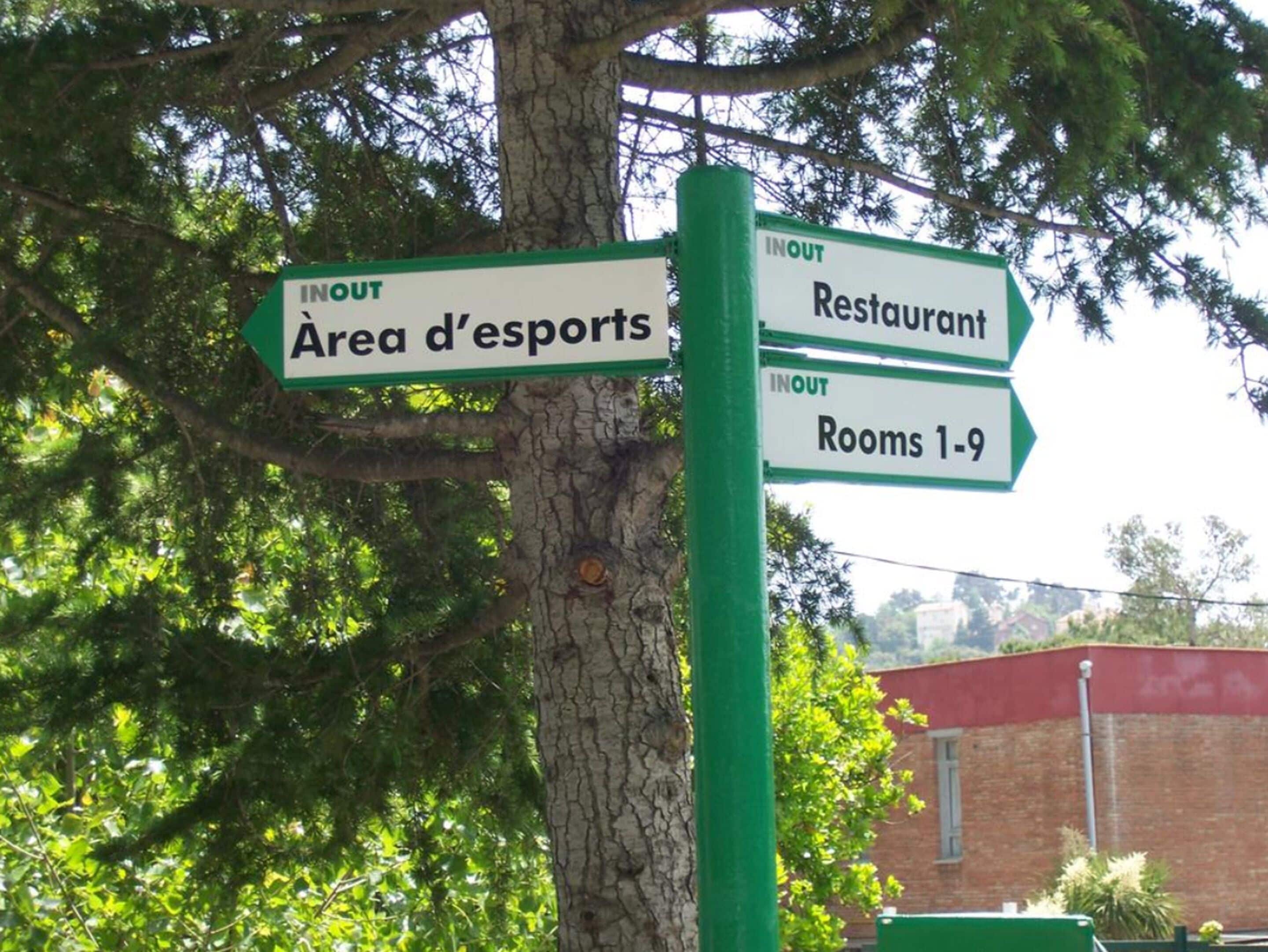 Un panneau indicateur avec les inscriptions « IN » et « OUT » pointant vers « Zone d’esports », « Restaurant » et « Chambres 1 à 9 ».