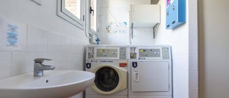 A laundry room with a sink, two washing machines, and a cabinet.