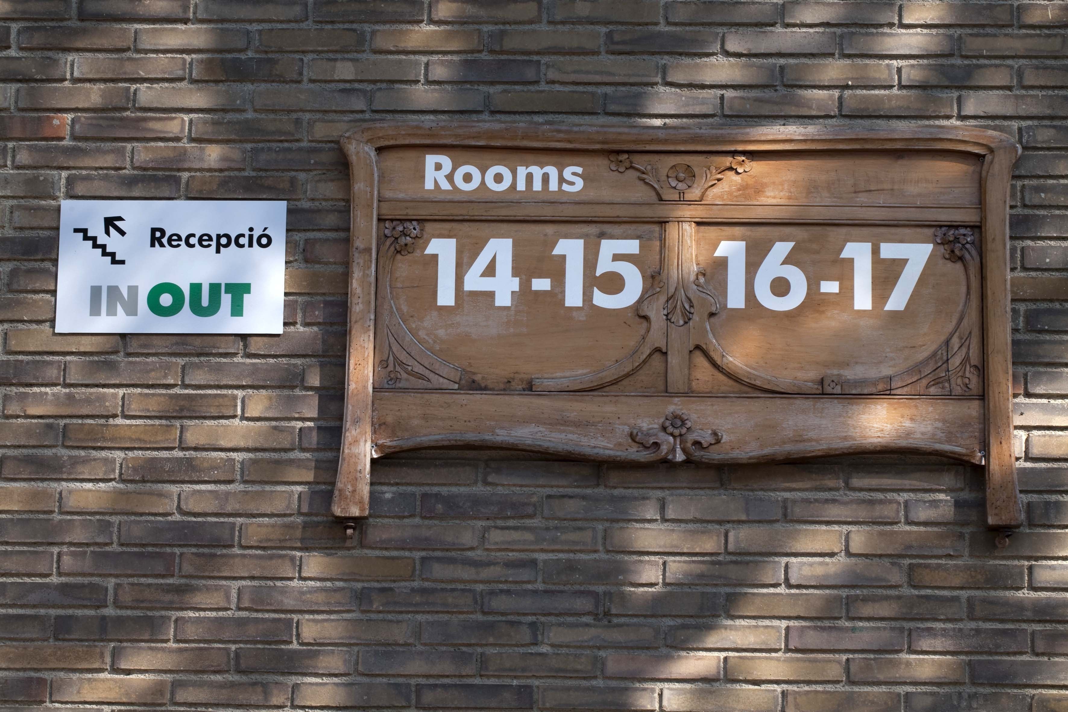 Señal que indica las habitaciones 14-15 y 16-17, con un cartel de recepción cerca.