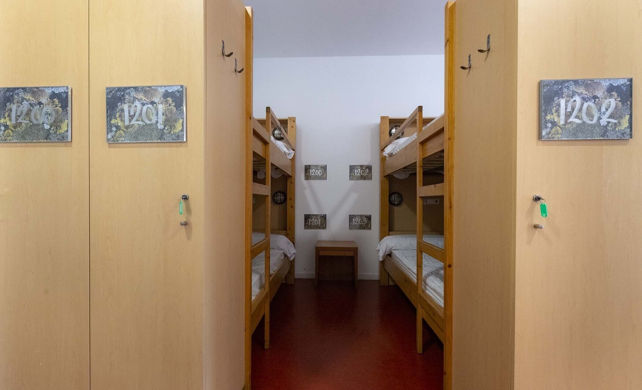 Una habitació de dormitori amb lliteres, indicadors amb els números de les habitacions i una taula petita.