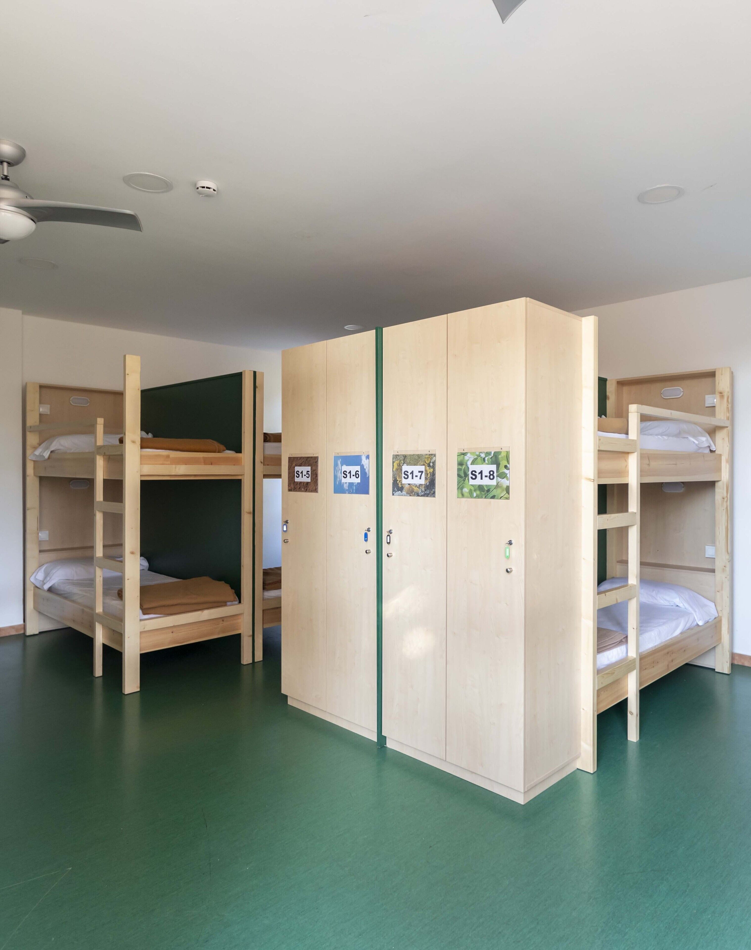 Una habitación con literas, ventilador de techo y suelo verde.