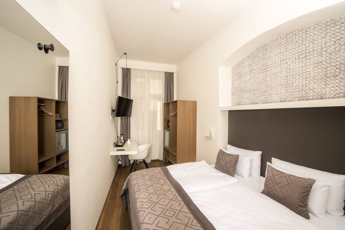 Una habitación de hotel con cama, escritorio y armario.