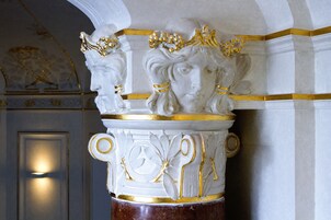 A marble column with gold accents and a decorative relief.